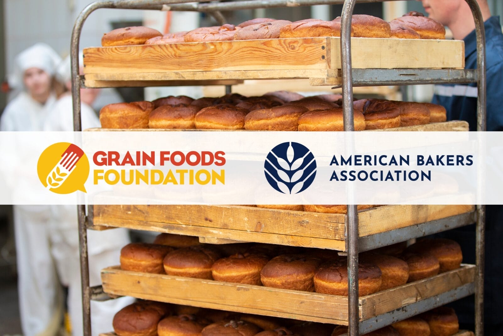Grain Foods Foundation and American Bakers Association logos on top of background image of bakers standing around rack of freshly baked bread loaves