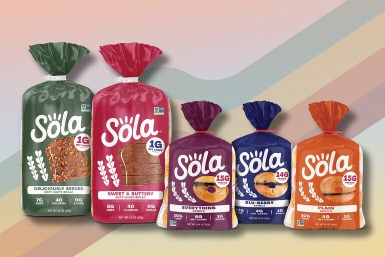 Packages of Sola bread on purple ombre background with rainbow stripes.