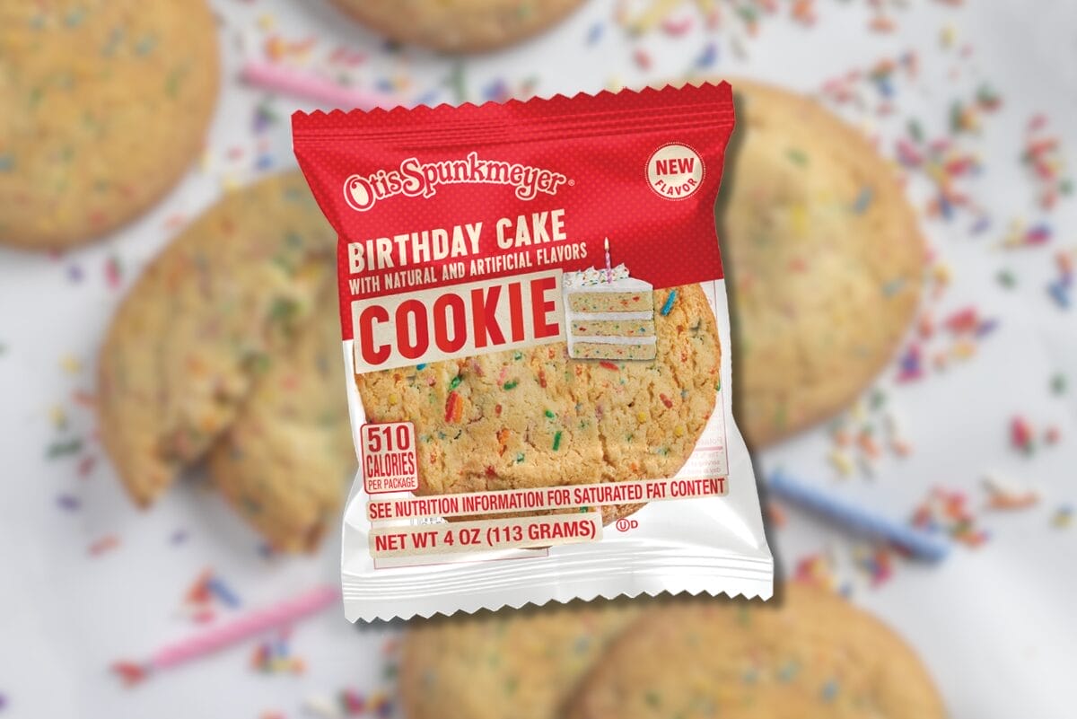 Otis Spunkmeyer individually wrapped Birthday Cake Cookie over blurry background with cookies and sprinkles on white surface