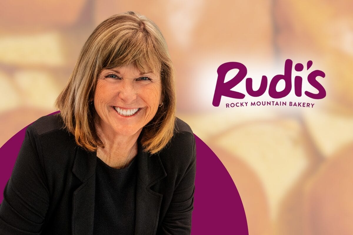 Jane Miller, CEO of Rudi's Rocky Mountain Bakery, next to Rudi's logo