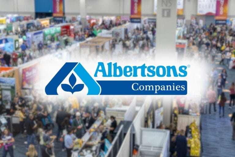 Albertsons Companies logo atop blurry image of Natural Products Expo West show floor