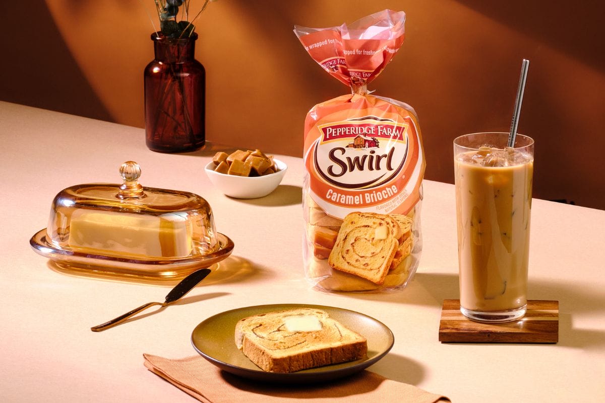 Bag of Pepperidge Farm Caramel Swirl Bread on table with iced coffee, toast and butter dish