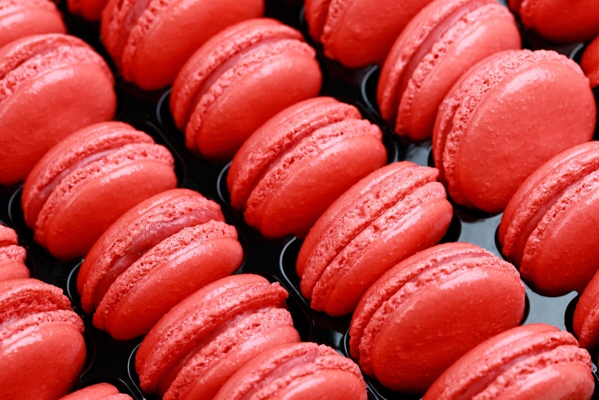 rows of bright red macarons on black tray